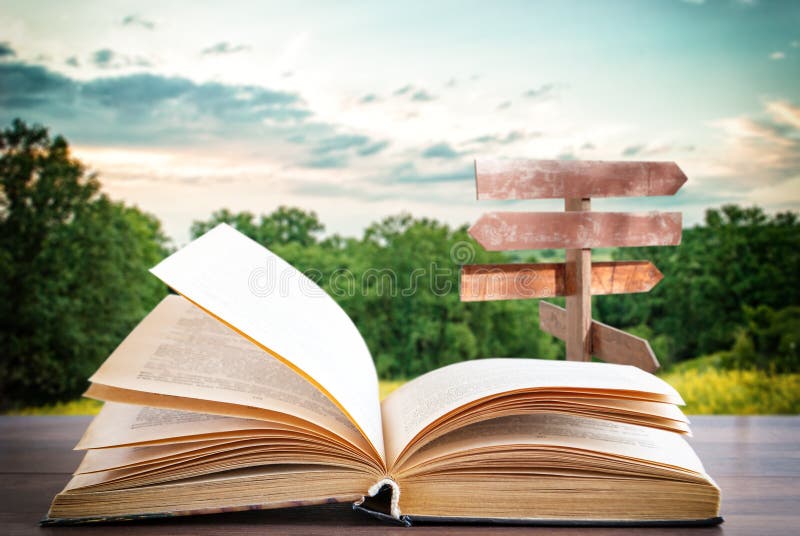 Livro aberto em uma superfície de madeira e um ponteiro no fundo foto de stock Livro aberto em uma superfície de madeira e um ponteiro no fundo foto de stock