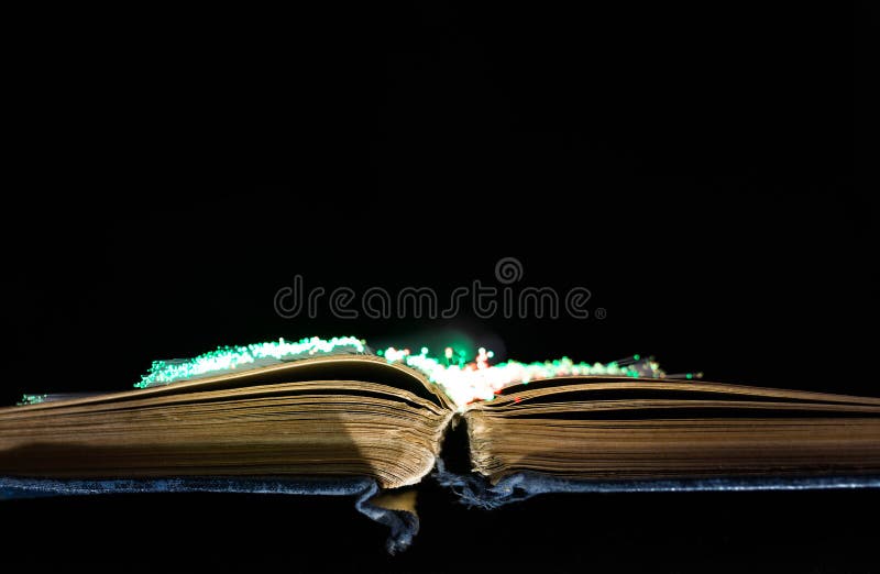 Livro aberto velho, envelhecido, amarelo, fibras óticas de incandescência imagem de stock royalty free Livro aberto velho, envelhecido, amarelo, fibras óticas de incandescência imagem de stock royalty free
