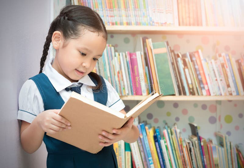 Livro de leitura bonito da menina do estudante asiático na biblioteca fotografia de stock Livro de leitura bonito da menina do estudante asiático na biblioteca fotografia de stock