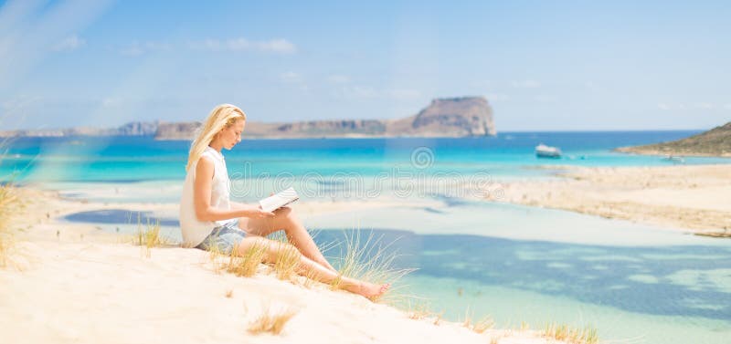 Livro de leitura da mulher, apreciando o sol na praia fotos de stock Livro de leitura da mulher, apreciando o sol na praia fotos de stock