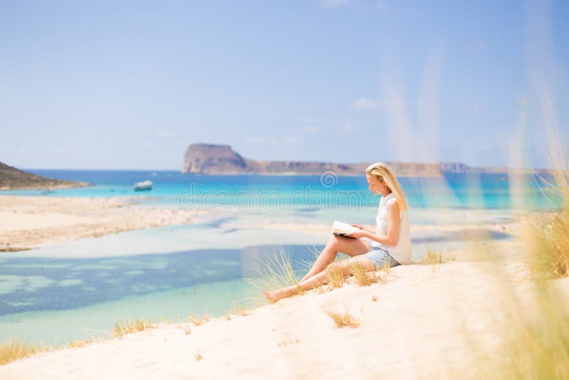 Livro de leitura da mulher, apreciando o sol na praia foto de stock Livro de leitura da mulher, apreciando o sol na praia foto de stock