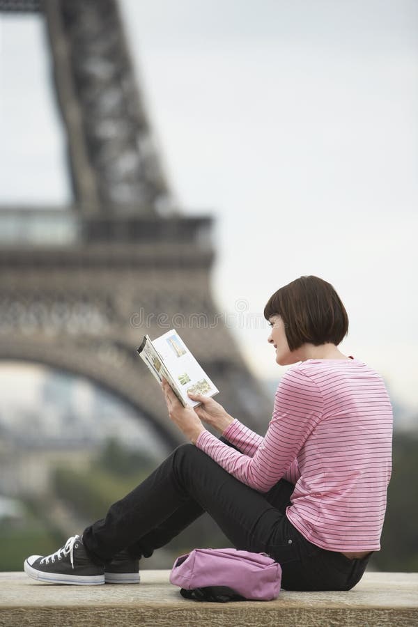 Livro de leitura da mulher em Front Of Eiffel Tower imagem de stock