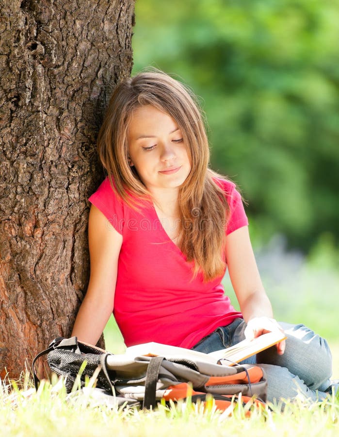 Livro de leitura feliz da menina do estudante imagens de stock Livro de leitura feliz da menina do estudante imagens de stock