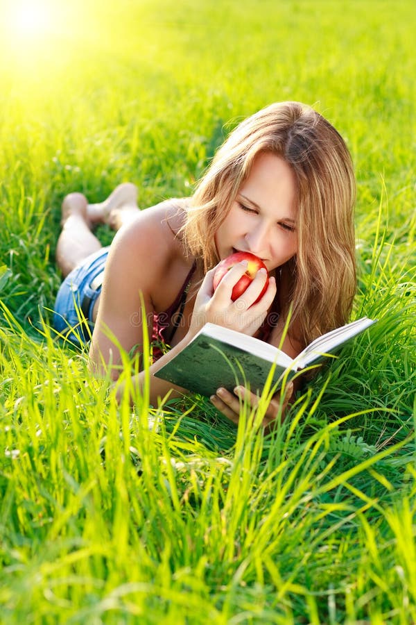 Livro de leitura feliz da mulher com Apple à disposicão foto de stock Livro de leitura feliz da mulher com Apple à disposicão foto de stock