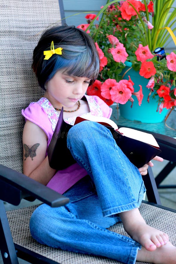 A little yuppie girl with kid tattoo and blue hair reading a bible. Shallow depth of field. A little yuppie girl with kid tattoo and blue hair reading a bible. Shallow depth of field.