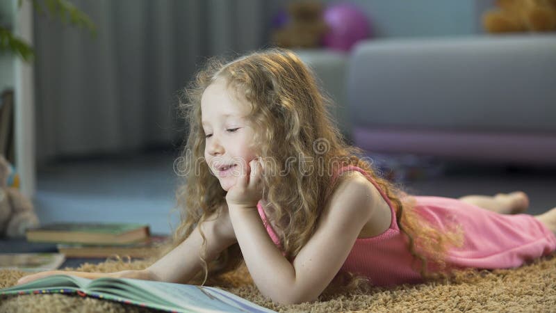 Livro favorito da leitura esperta da menina em casa no seus próprios, infância feliz