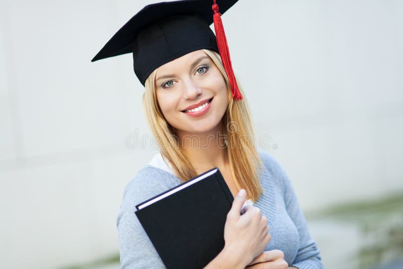 Smiling female graduate holding book. Smiling female graduate holding book