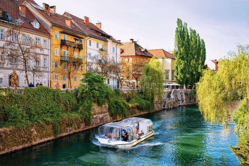 Ljubljana, Eslovenia - 27 de abril de 2018: Barco de la excursión en el río de Ljubljanica en el centro histórico de Ljubljana, E imagenes de archivo Ljubljana, Eslovenia - 27 de abril de 2018: Barco de la excursión en el río de Ljubljanica en el centro histórico de Ljubljana, E imagenes de archivo