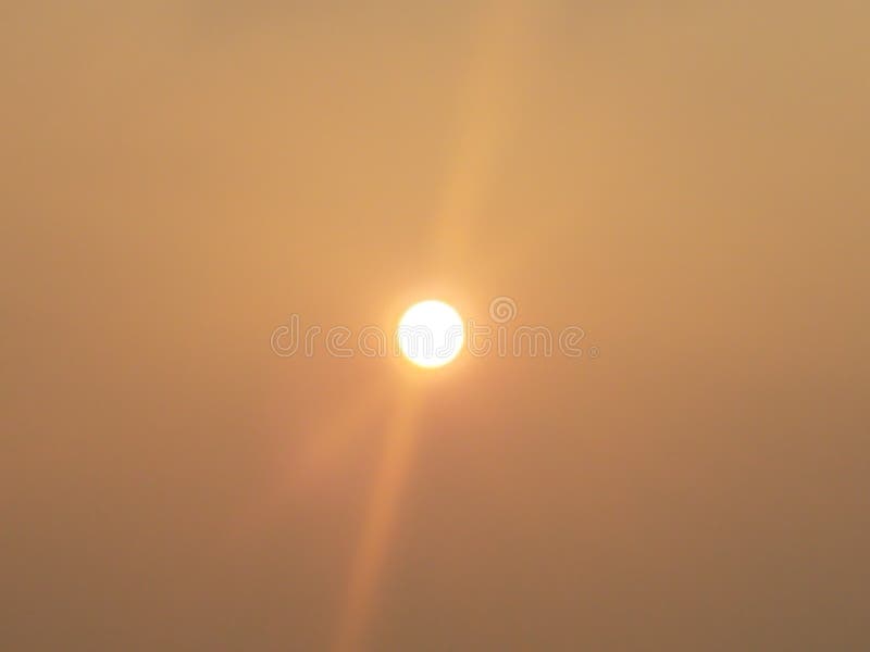 Bright yellow and orange sun with glare and cloudy sky. Bright yellow and orange sun with glare and cloudy sky
