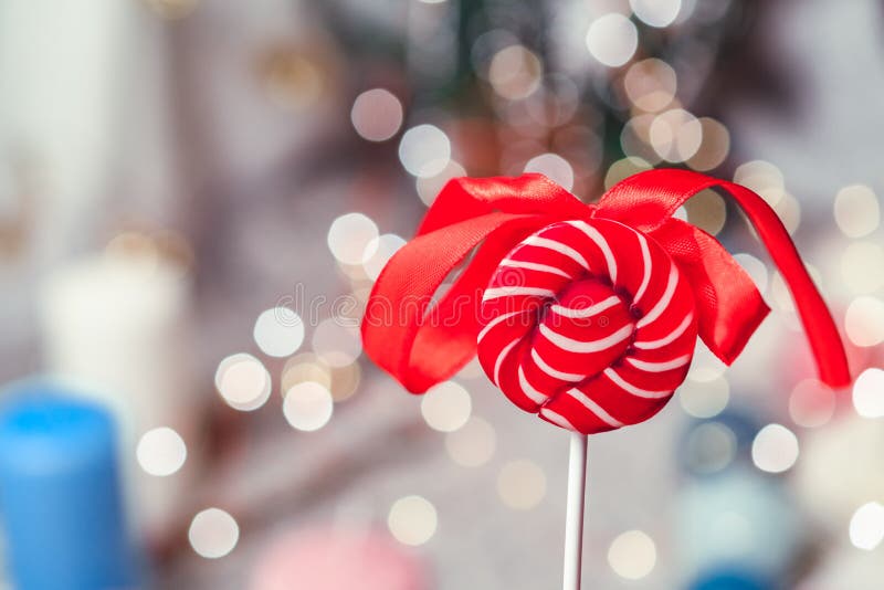 Ljus röd rund godis med en pilbåge mot bakgrunden av bokeh royaltyfri bild Ljus röd rund godis med en pilbåge mot bakgrunden av bokeh royaltyfri bild