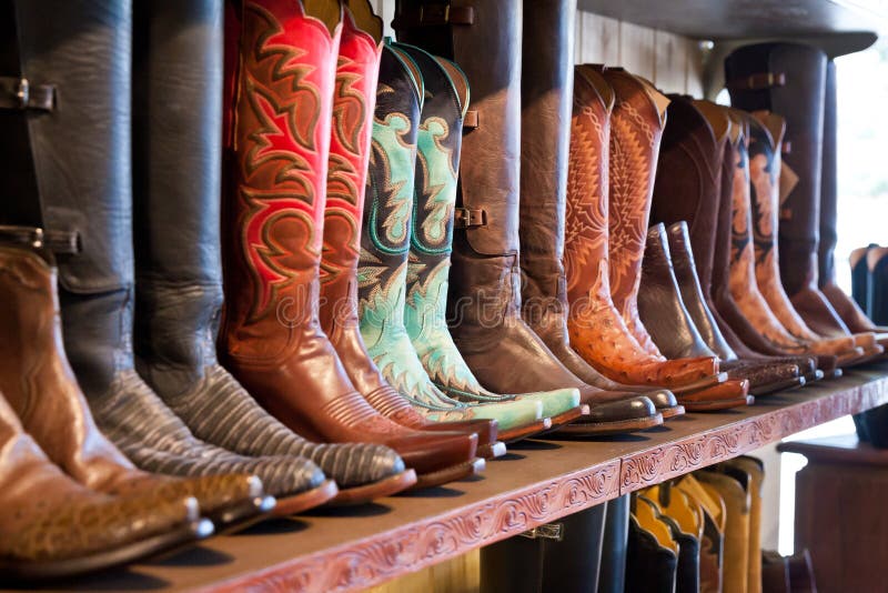 Ljusa skinande cowboykängor som står på en hylla i hantverk, shoppar royaltyfria foton