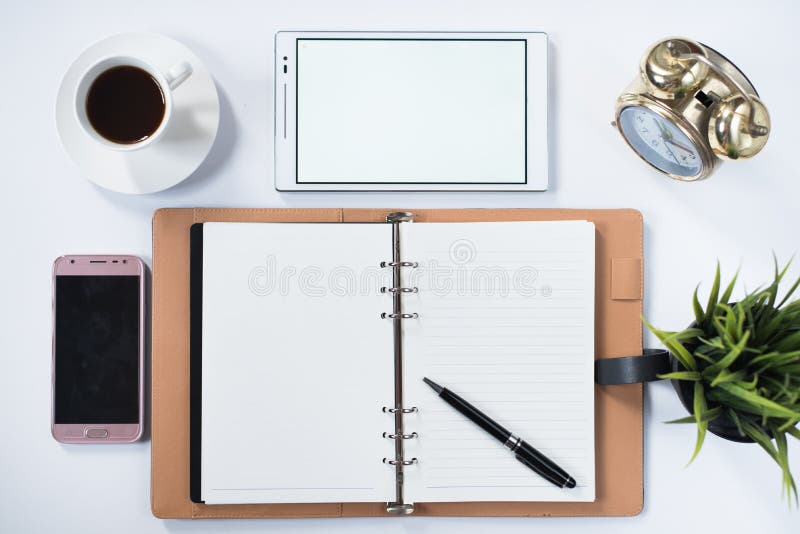 Llame por teléfono, tableta digital, reloj, planta, cojín de nota y esconda el cuaderno con en la endecha blanca del plano imagenes de archivo Llame por teléfono, tableta digital, reloj, planta, cojín de nota y esconda el cuaderno con en la endecha blanca del plano imagenes de archivo