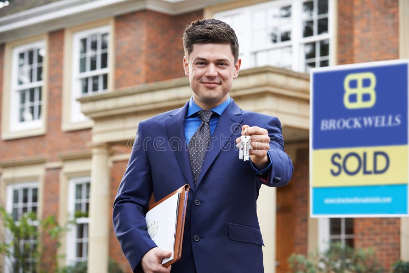 Llaves residenciales de la tenencia de propiedad del exterior derecho masculino del agente inmobiliario imagenes de archivo Llaves residenciales de la tenencia de propiedad del exterior derecho masculino del agente inmobiliario imagenes de archivo