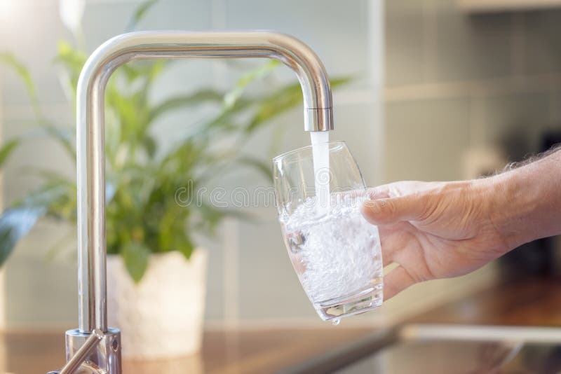 Llenando un vaso con agua potable de la llave de la cocina