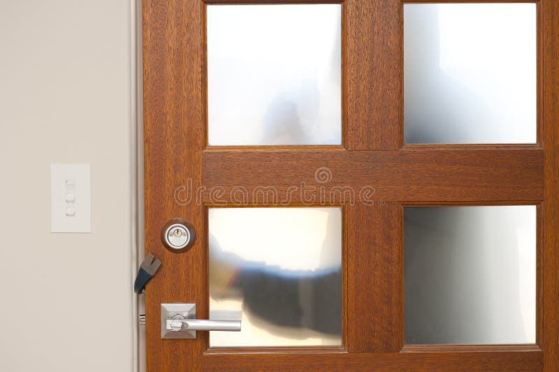 Burglar, thief with gloves, holding crowbar trying to break in home, unlock door, blurred visible silhouette behind milky windows, with copy space. Burglar, thief with gloves, holding crowbar trying to break in home, unlock door, blurred visible silhouette behind milky windows, with copy space.