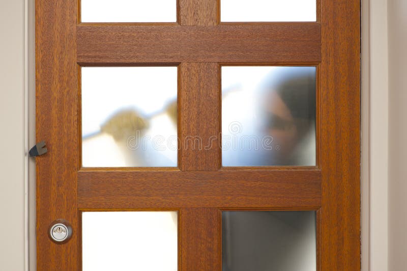 Burglar, thief with gloves, holding crowbar trying to break in home, unlock door, blurred visible silhouette behind milky windows, with copy space. Burglar, thief with gloves, holding crowbar trying to break in home, unlock door, blurred visible silhouette behind milky windows, with copy space.