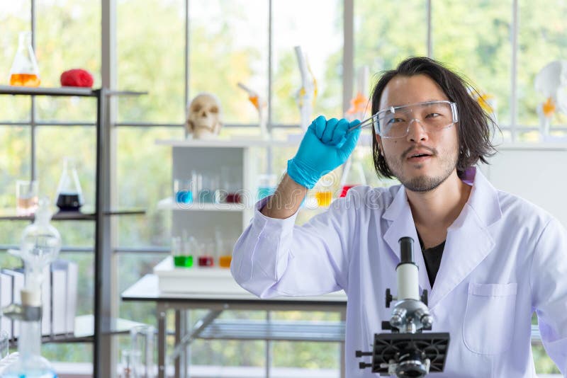 Lo scienziato asiatico intelligente si sente sorpreso e soddisfatto del suo nuovo prodotto di ricerca, tablet pill in un laborato immagine stock Lo scienziato asiatico intelligente si sente sorpreso e soddisfatto del suo nuovo prodotto di ricerca, tablet pill in un laborato immagine stock