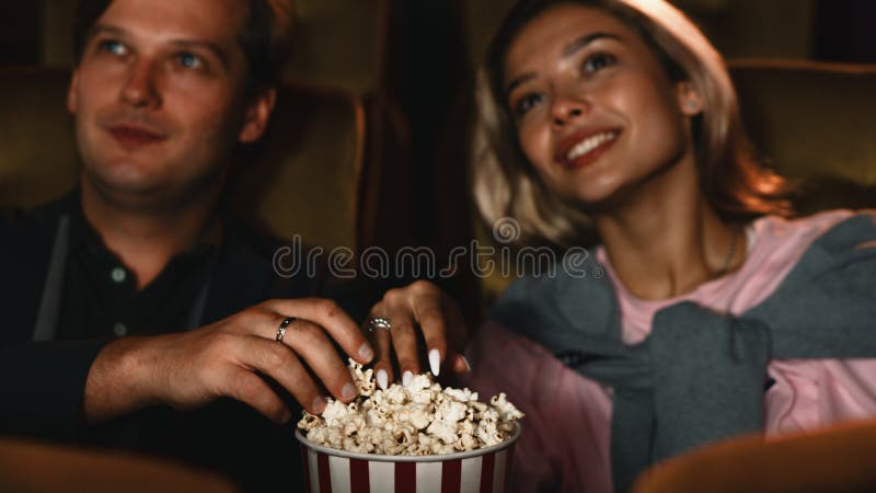Lo sfondo di cibo di un secchio di popcorn con le mani di una coppia di innamorati caucasici si sta alzando per mangiare come spu fotografia stock libera da diritti