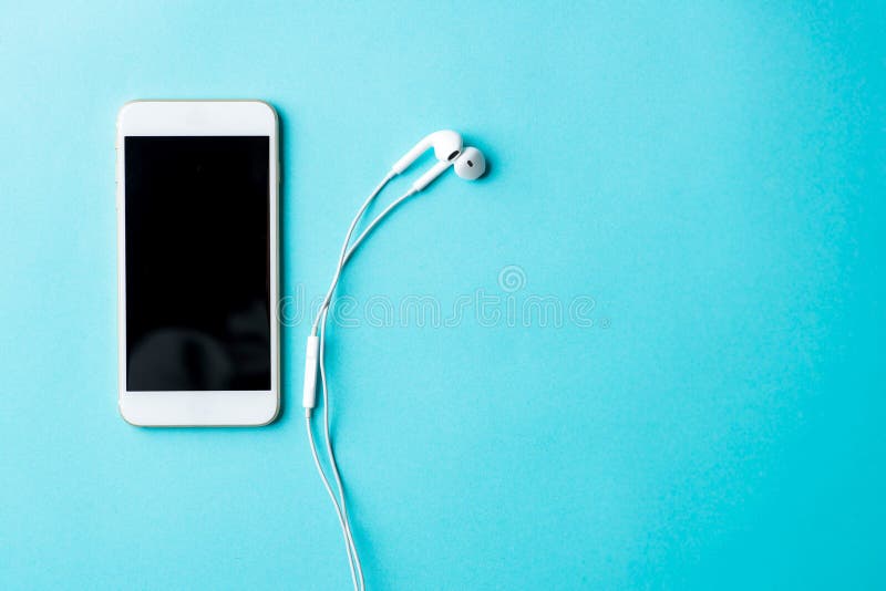 Lo smartphone bianco con lo schermo nero del modello e le cuffie sono su w fotografia stock libera da diritti Lo smartphone bianco con lo schermo nero del modello e le cuffie sono su w fotografia stock libera da diritti