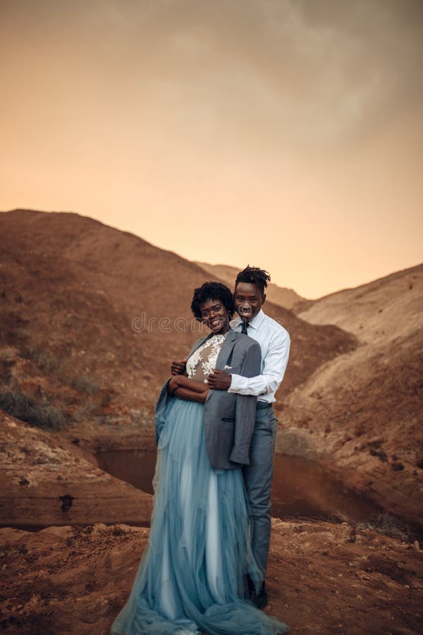 Lo sposo abbraccia la sua sposa vestita in suo rivestimento in canyon al tramonto fotografia stock libera da diritti Lo sposo abbraccia la sua sposa vestita in suo rivestimento in canyon al tramonto fotografia stock libera da diritti