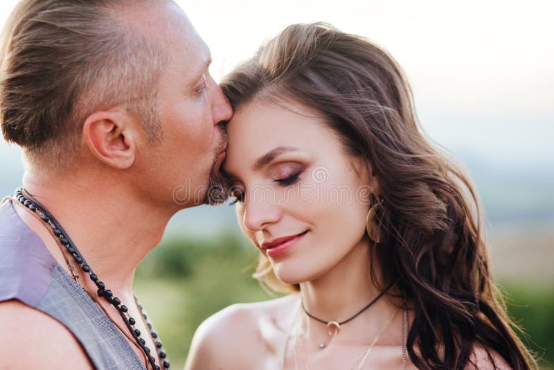 Lo sposo si è vestito nello stile del boho delicatamente bacia la sposa fotografia stock Lo sposo si è vestito nello stile del boho delicatamente bacia la sposa fotografia stock