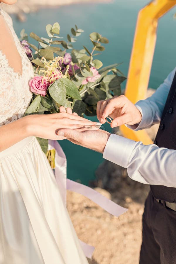 Lo sposo veste l'anello per il ponte a una cerimonia nuziale su una spiaggia in mare Mani nuove e ravvicinate fotografie stock libere da diritti Lo sposo veste l'anello per il ponte a una cerimonia nuziale su una spiaggia in mare Mani nuove e ravvicinate fotografie stock libere da diritti