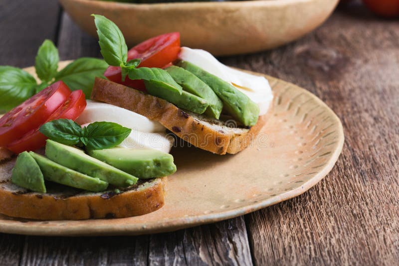 Lo stile dell'insalata di Caprese tosta con l'avocado sul piatto ceramico fotografia stock Lo stile dell'insalata di Caprese tosta con l'avocado sul piatto ceramico fotografia stock