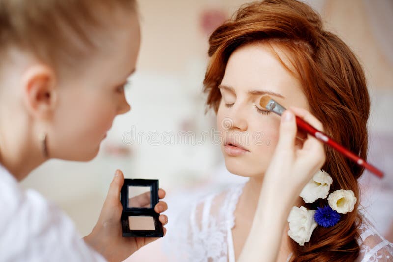 Lo stilista fa la sposa di trucco sul giorno delle nozze fotografia stock Lo stilista fa la sposa di trucco sul giorno delle nozze fotografia stock