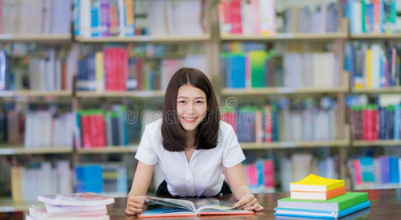 Lo studente asiatico di signora ha letto un libro nella biblioteca della città universitaria in Universit