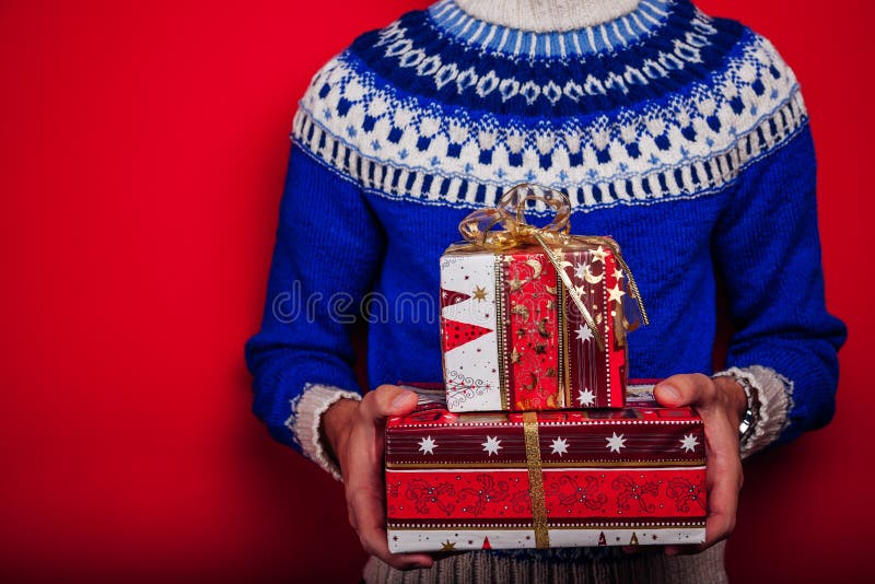Lo studio ha sparato di un giovane in maglione islandese che tiene un mucchio dei contenitori di regalo Concetto di celebrazione fotografie stock libere da diritti Lo studio ha sparato di un giovane in maglione islandese che tiene un mucchio dei contenitori di regalo Concetto di celebrazione fotografie stock libere da diritti