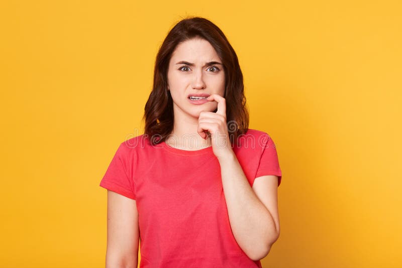 Lo studio sparato del giovanotto femminile che è pieno di timore, tiene il dito anteriore vicino alle labbra, essendo in profondi immagine stock