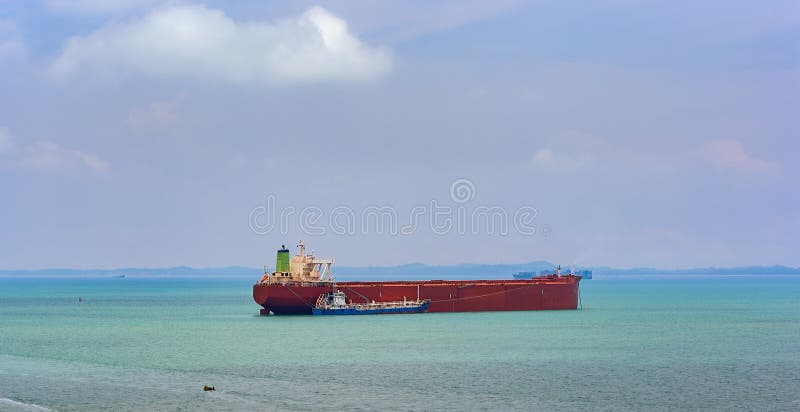 Loading anchored oil supertanker via a ship-to-ship oil transfer. Refuelling or bunkering in marine terms is carried out using a small raid tanker to pump the bunker fuel into the bigger ship via a ship-to-ship oil transfer (STS).