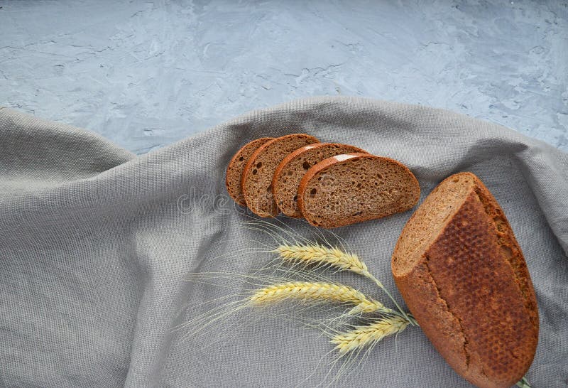 Loaf av slitna rågbröd, vetekryddor, med en grå bakgrund på en gammal träskiva, kopieringsutrymme royaltyfria bilder
