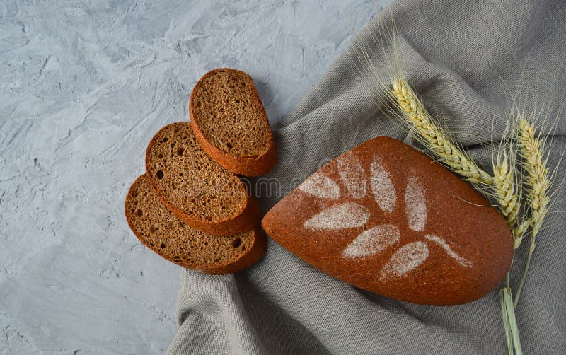 Loaf av slitna rågbröd, vetekryddor, med en grå bakgrund på en gammal träskiva, kopieringsutrymme royaltyfri fotografi