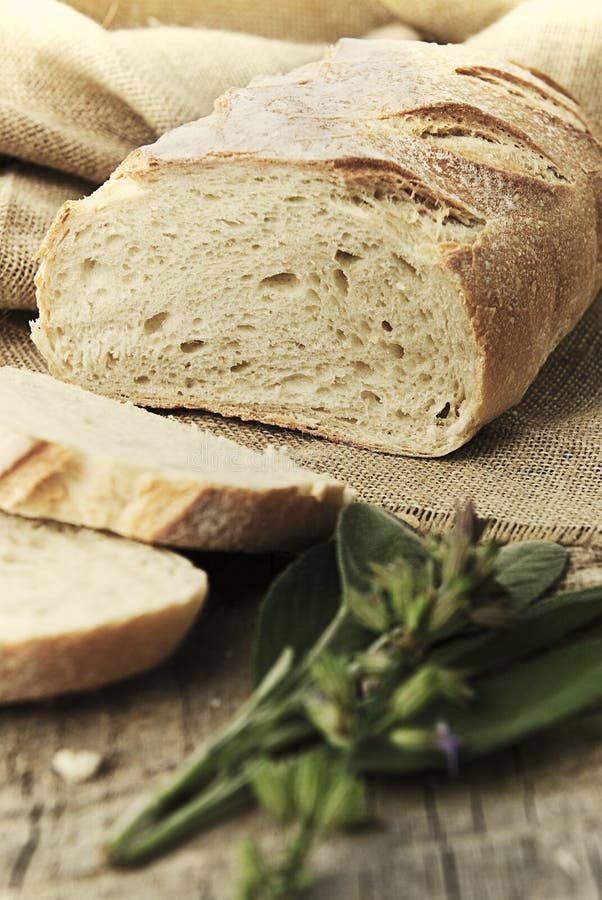 Freshly baked loaf of bread, just sliced with fresh herbs.