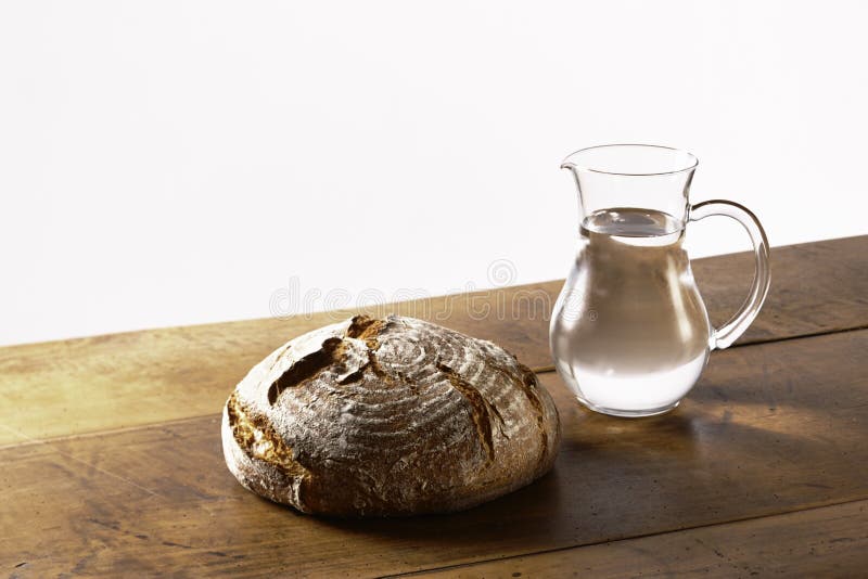 A loaf of bread and a jug of water on table