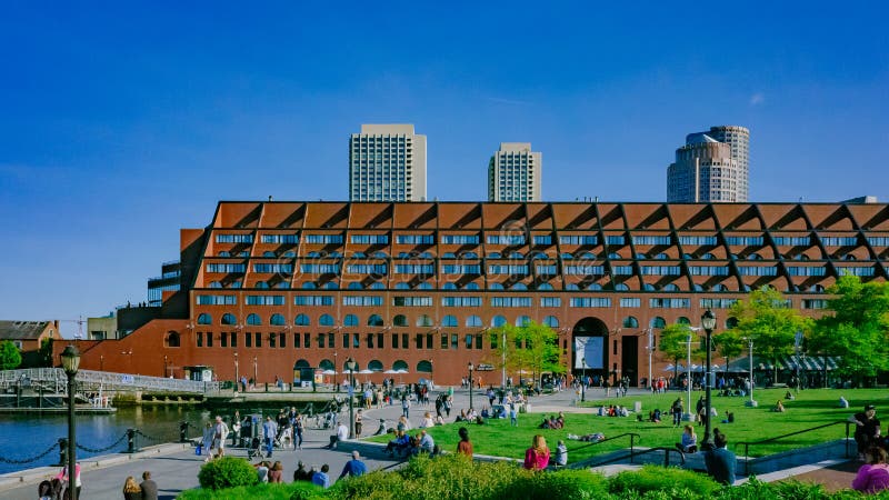 Locali che godono di un giorno soleggiato di inizio dell'estate in Christopher Columbus Waterfront Park a Boston del centro fotografie stock Locali che godono di un giorno soleggiato di inizio dell'estate in Christopher Columbus Waterfront Park a Boston del centro fotografie stock