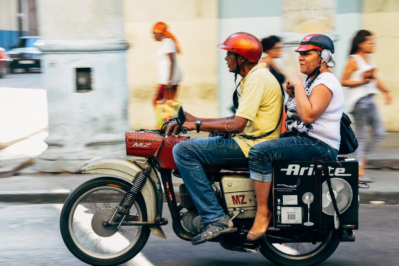 Locals riding a classic motorbike in Cuba. stock image Locals riding a classic motorbike in Cuba. stock image