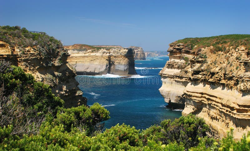 A scenic rocky cliff view of Loch Ard Gorge, Port Cambell National Park from Muttonbird Island lookout east across Elephant Rock, Lock Ard Wreck lookout, Island Archway and ending at the Razorback exposing the striking blue waters and lush green growth on a sunny Feburary day at near the Great Ocean Road in Victoria, southern Australia. A scenic rocky cliff view of Loch Ard Gorge, Port Cambell National Park from Muttonbird Island lookout east across Elephant Rock, Lock Ard Wreck lookout, Island Archway and ending at the Razorback exposing the striking blue waters and lush green growth on a sunny Feburary day at near the Great Ocean Road in Victoria, southern Australia.