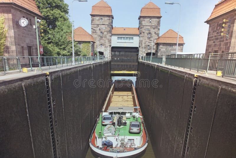 Lock with long ship and two towers in the bakground . Cargo Boat is at the bottom of the lock ready to float upstairs . Bratislava