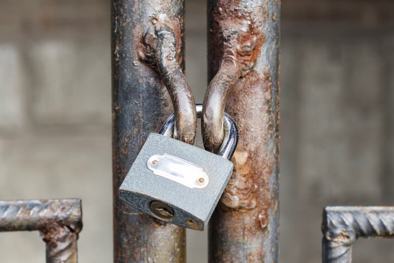 Locked lock old rusty metal door close up. Antique slide steel locked shutter door. The lock, on the grating, closed