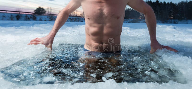 Young man bathing in the ice hole. Focus on the ice in a water only. Young man bathing in the ice hole. Focus on the ice in a water only