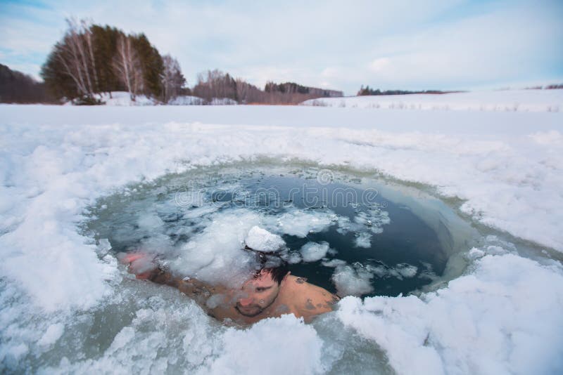 Young man swimming in the winter lake in the ice hole. Young man swimming in the winter lake in the ice hole