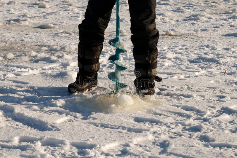 Man in cold winter day make ice-hole for winter fishing. Man in cold winter day make ice-hole for winter fishing