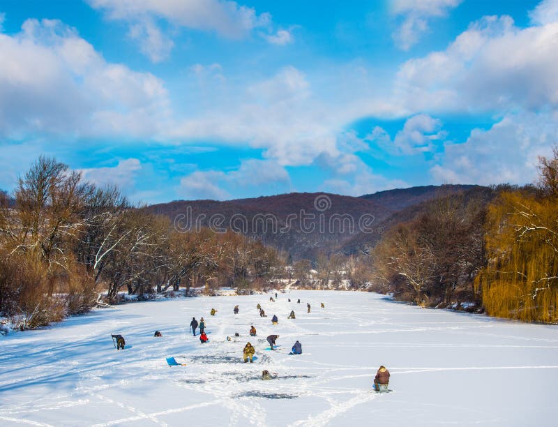 Many people ice fishing on a frozen river in winter sunny day. Many people ice fishing on a frozen river in winter sunny day