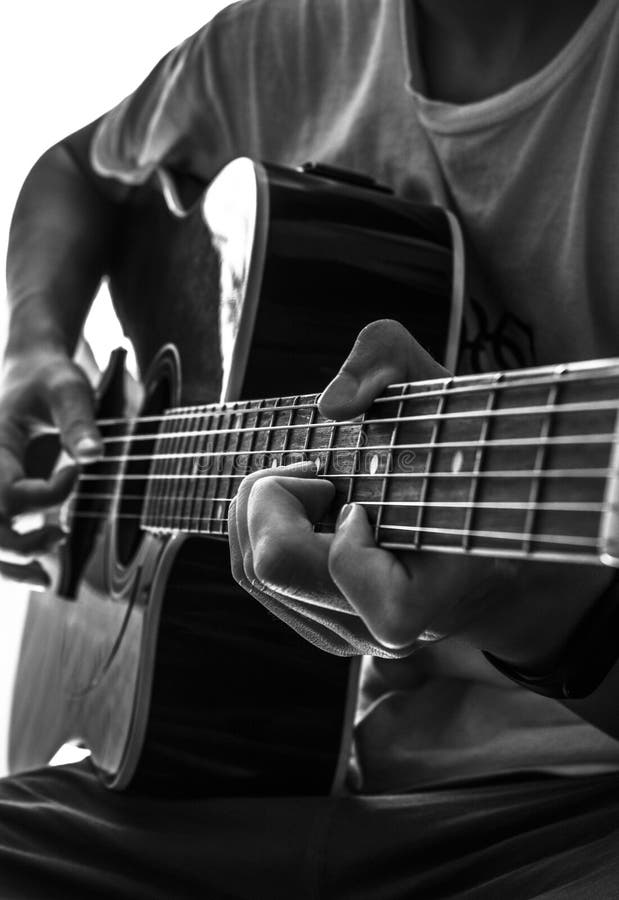 Lodrät gråskalebild av en man som leker på gitarr royaltyfri bild