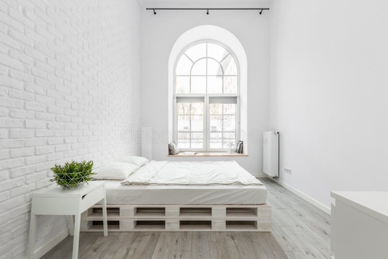 Loft bedroom with white brick wall, pallet bed and half circle window. Loft bedroom with white brick wall, pallet bed and half circle window