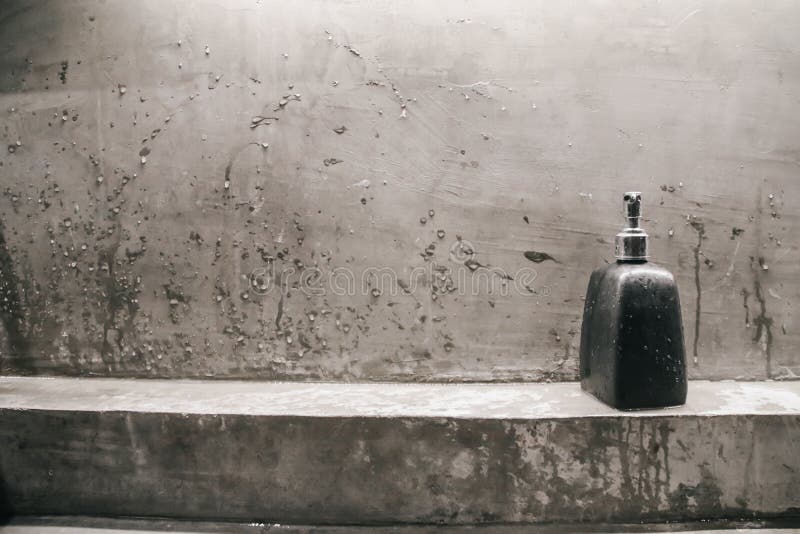 Loft style bathroom interior.Soap dispensers near water tap sink with faucet on concrete wall, vertical style