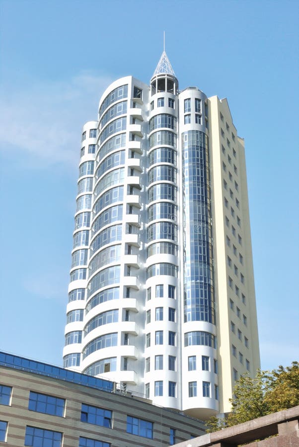 The lofty white building is against light blue sky