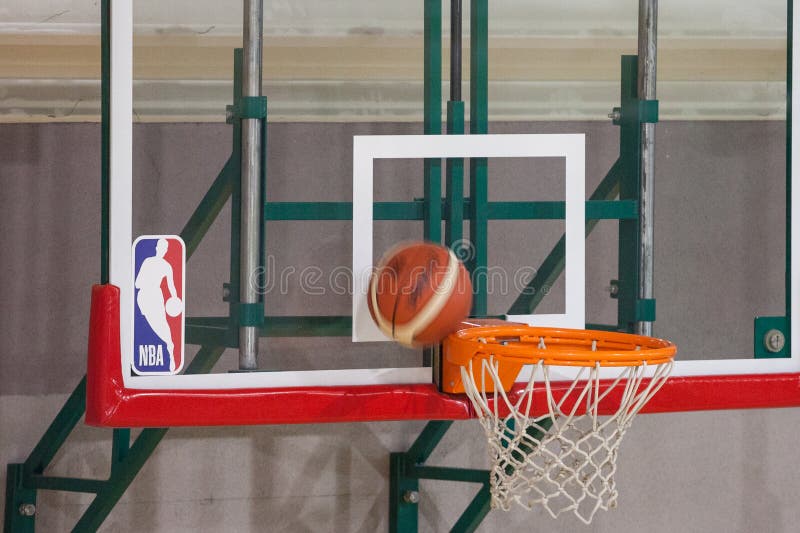 Logo di NBA su un piano di sostegno mentre una pallacanestro si accinge al punteggio sul suo anello immagini stock Logo di NBA su un piano di sostegno mentre una pallacanestro si accinge al punteggio sul suo anello immagini stock